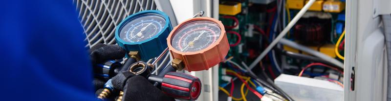 Manifold gauges checking refrigerant pressures during AC maintenance