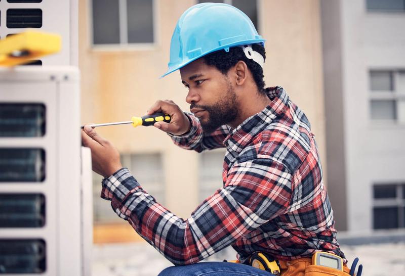 Handyman with a tool belt using a screwdriver on home equipment